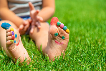 Naklejka premium Child feet drawing smile in the park on the grass. Selective focus.