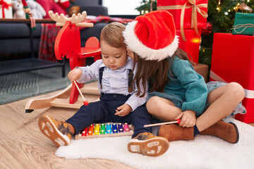 Adorable boy and girl playing xylophone celebrating christmas kissing at home