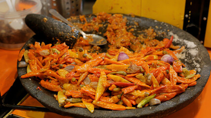 In the mortar and pestle there are lots of cayenne peppers and shallots