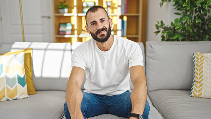 Young hispanic man smiling confident sitting on sofa at home