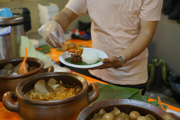 Obraz na płótnie Canvas A man serves buyers typical Yogyakarta gudeg rice and side dishes, nasi gudeg