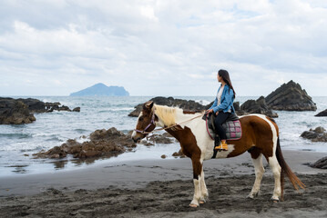 Tourist woman ride a horse beside the sea beach