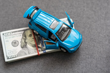 A toy car and banknotes lie, the cost of operating a car.