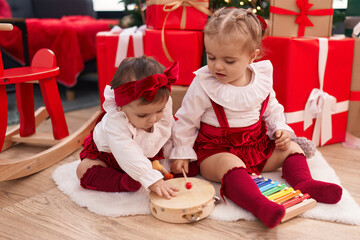 Adorable girls playing xylophone and tambourine celebrating christmas at home