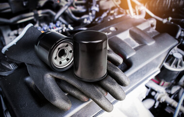 Engine oil filter and auto mechanic gloves on engine cover in a engine compartment for car engine maintenance , Car maintenance service concept - obrazy, fototapety, plakaty