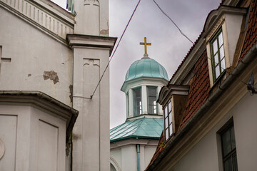 Fototapeta na wymiar Gold christian cross shining in the top of a bright blue tower orthodox church in Latvia, Riga