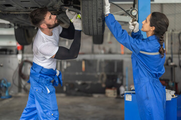 Car technicians analyze, fix wheel issues in garage, using precise tools for optimal alignment.