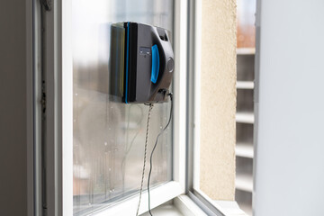 Crop of smart vacuum cleaner washing windows. Home appliance and technology concept