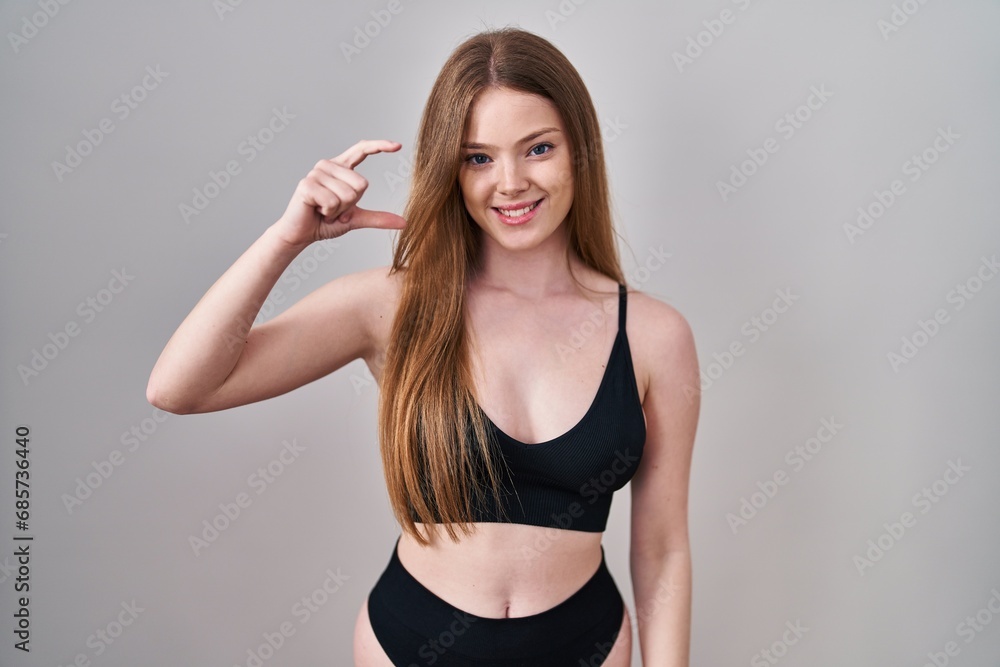 Canvas Prints Young caucasian woman wearing lingerie smiling and confident gesturing with hand doing small size sign with fingers looking and the camera. measure concept.