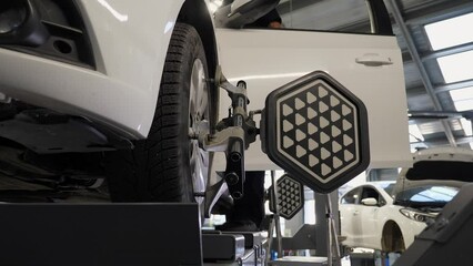 Diagnostics and balancing of wheels on a lift in close-up at a modern service station. Checking the wheel balancing on the lifting machine with the help of special equipment, the wheels rotate slowly.
