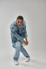 attractive emotional african american man in stylish denim outfit gesturing lively, fashion concept