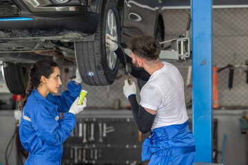 Car technicians analyze, fix wheel issues in garage, using precise tools for optimal alignment.