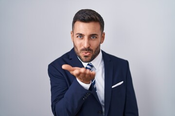 Handsome hispanic man wearing suit and tie looking at the camera blowing a kiss with hand on air being lovely and sexy. love expression.
