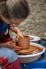 A woman working on the clay wheel creating a new piece.