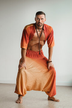 a man in an orange suit does yoga by moving his abdominal muscles in the gym. The concept of health