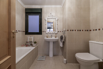 Bathroom with bathtub without screens or curtains, white porcelain sink with matching pedestal and...