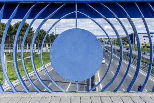 A metal railing with a peculiar structure painted blue on an access highway to the city