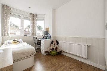 A youth room decorated with white furniture, a long radiator on the wall, a huge stuffed animal and a beautiful glass window