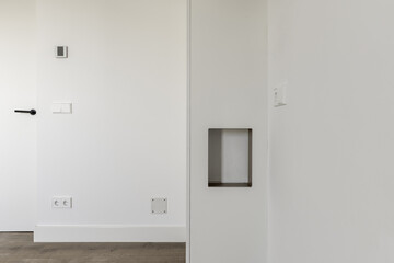 Walls of a room with freshly applied white paint, sockets, light boxes and temperature regulator