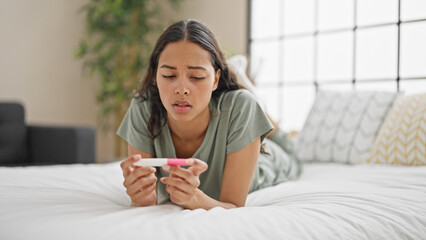 African american woman holding pregnancy test lying on bed at bedroom © Krakenimages.com