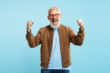 Portrait of excited mature man, bearded hipster screaming, holding hands up, celebration success...