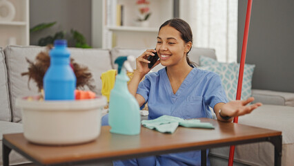 African american woman professional cleaner cleaning table talking on smartphone at home