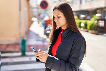 Young beautiful hispanic woman using smartphone with serious expression at street