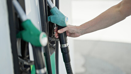 Middle age woman holding fuel at petrol station