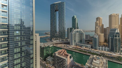Fototapeta na wymiar Panorama showing Dubai Marina with several boats and yachts parked in harbor and skyscrapers around canal aerial morning timelapse.