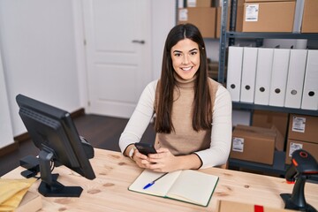 Young beautiful hispanic woman ecommerce business worker using smartphone at office