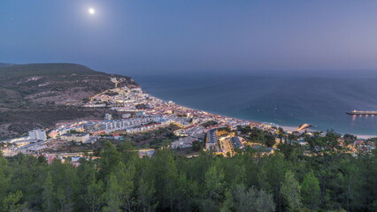 Obraz premium Aerial view of the coastline of the village of Sesimbra day to night timelapse. Portugal