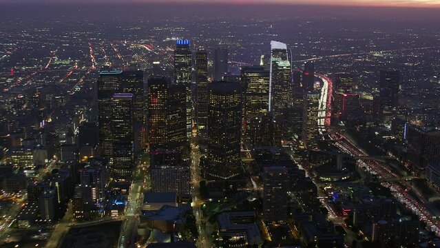 Magnificent Aerial View of Los Angeles at Sunset. Skyscrapers in the Financial District and 110 Freeway Full of Cars. United Sates. California.  Blurred Brands and Logos. Shot from Helicopter in 8K. 
