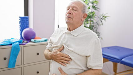 Mature senior man meditating with calm breath touched by therapeutic care at rehab clinic, adult...