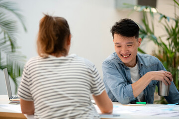 Cheerful young adult man discussing over paper work with coworker