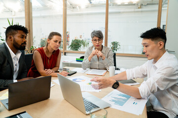 Young adult businessman presenting work to coworkers