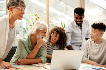 Coworkers discussing over laptop during meeting