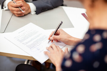 High angle view close up of adult woman signing a contract during meeting