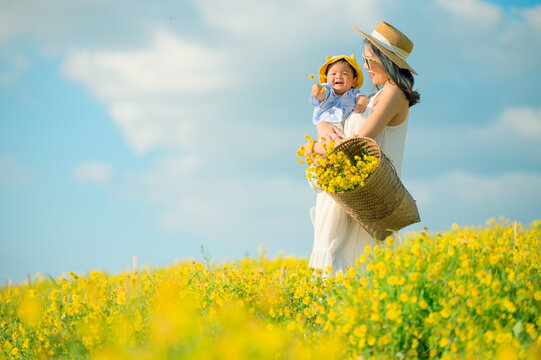 Mother with little child in flower blooming garden. woman with son in green leaves,happy family outdoors in spring