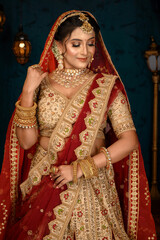 Stunning Indian bride dressed in traditional bridal lehenga with heavy gold jewellery and veil...