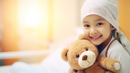 A girl with cancer smiles while hugging a teddy bear