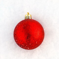 Christmas decorations. Red ball on natural white snow. New year winter concept. Top view, copy space, flat lay.
