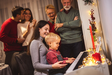 Granddaughter and grandson playing a piano for their family on Christmas Eve.