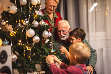 Family decorating together a tree with lights and balls. Christmas time.