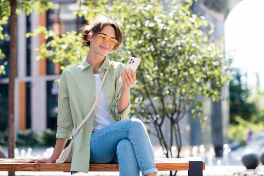 Photo of adorable girl dressed stylish clothes sitting on bench have free time waiting meeting date with boyfriend
