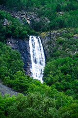 Fototapeta na wymiar Vertical realistic view of powerful waterfall falling from mountains in Norway