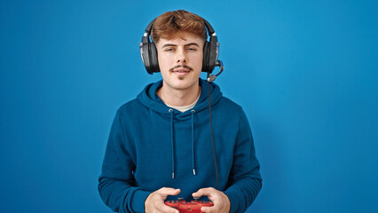 Young hispanic man playing video game over isolated blue background
