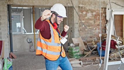 Young hispanic man builder smiling confident dancing at construction site