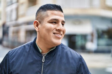 Young latin man smiling confident looking to the side at street
