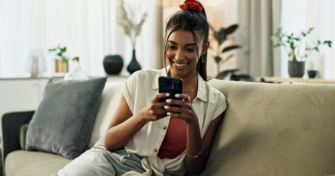 Woman, phone and communication with smile on couch for conversation, typing or email in living room of home. Indian, person and smartphone for texting with internet or technology on sofa in lounge