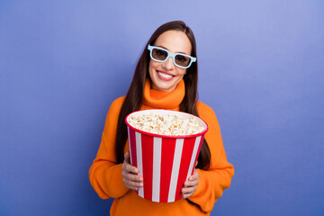 Photo of smiling happy woman wear orange knitted pullover 3d glasses for movies holding popcorn isolated on violet color background